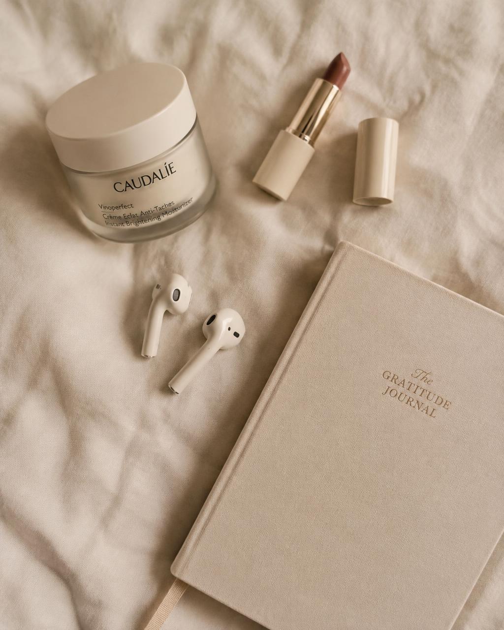 Skincare and earbuds on linen